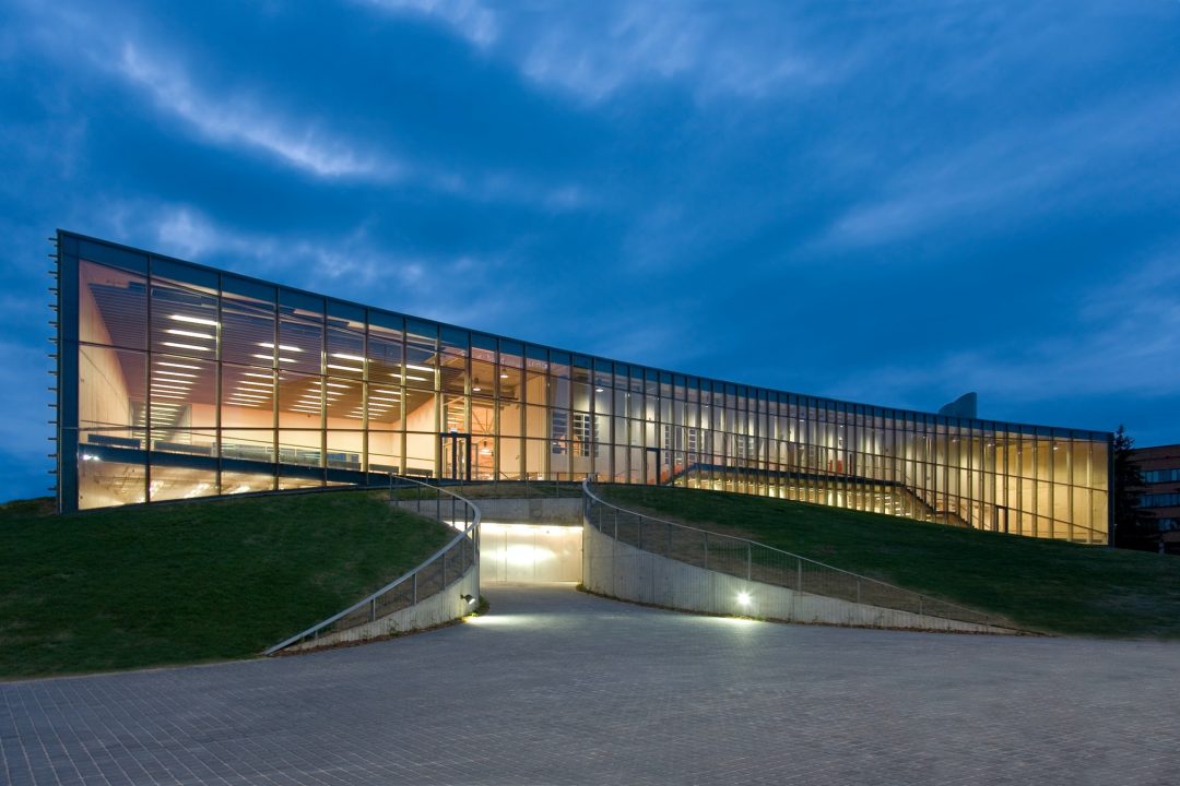 modern-university-buildings-glass-facade-lit-up-at-night-on-a-curved-ground-surface.jpg